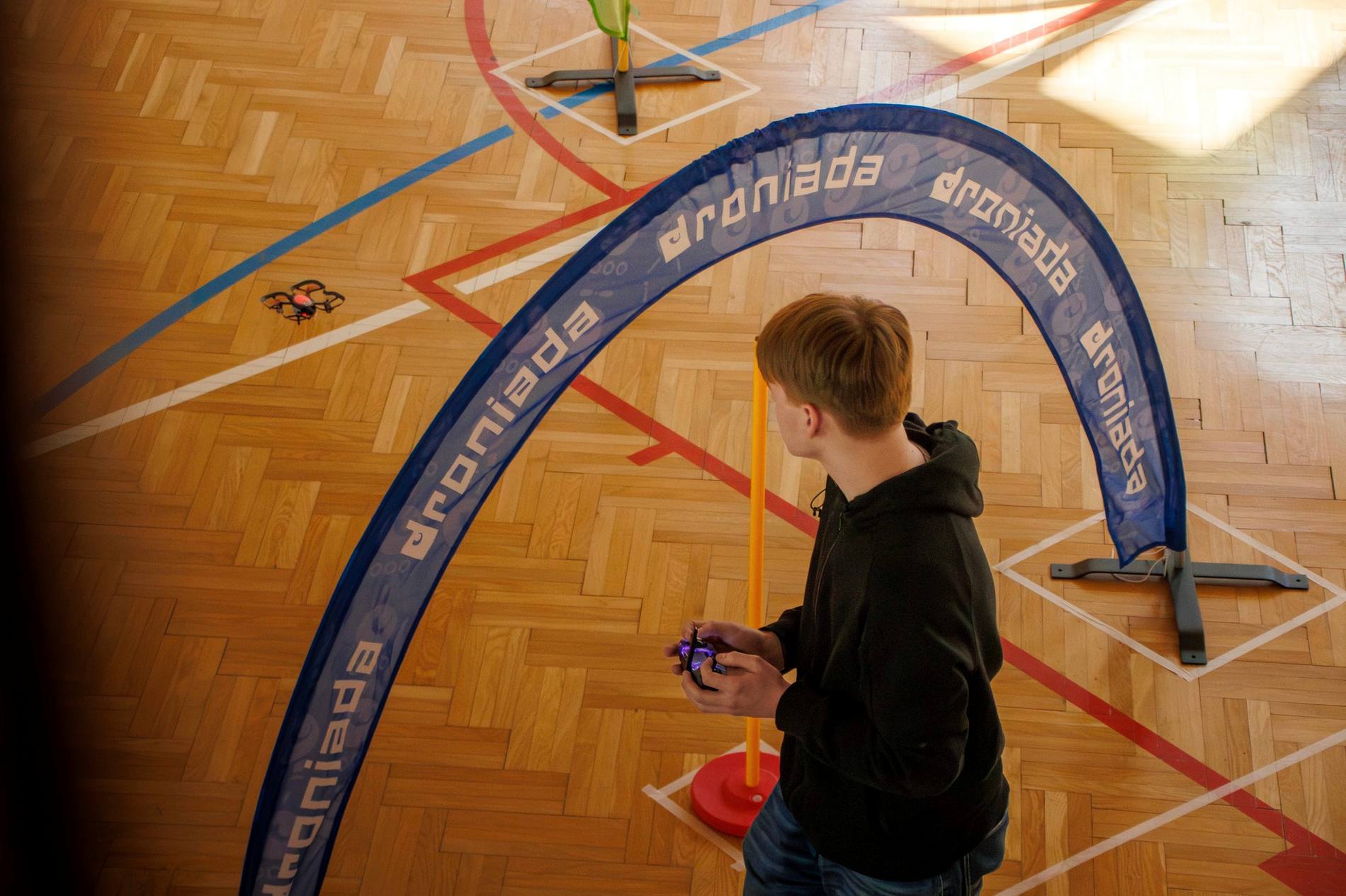 Uczestnik turnieju Droniada Junior przelatuje dronem przez bramkę